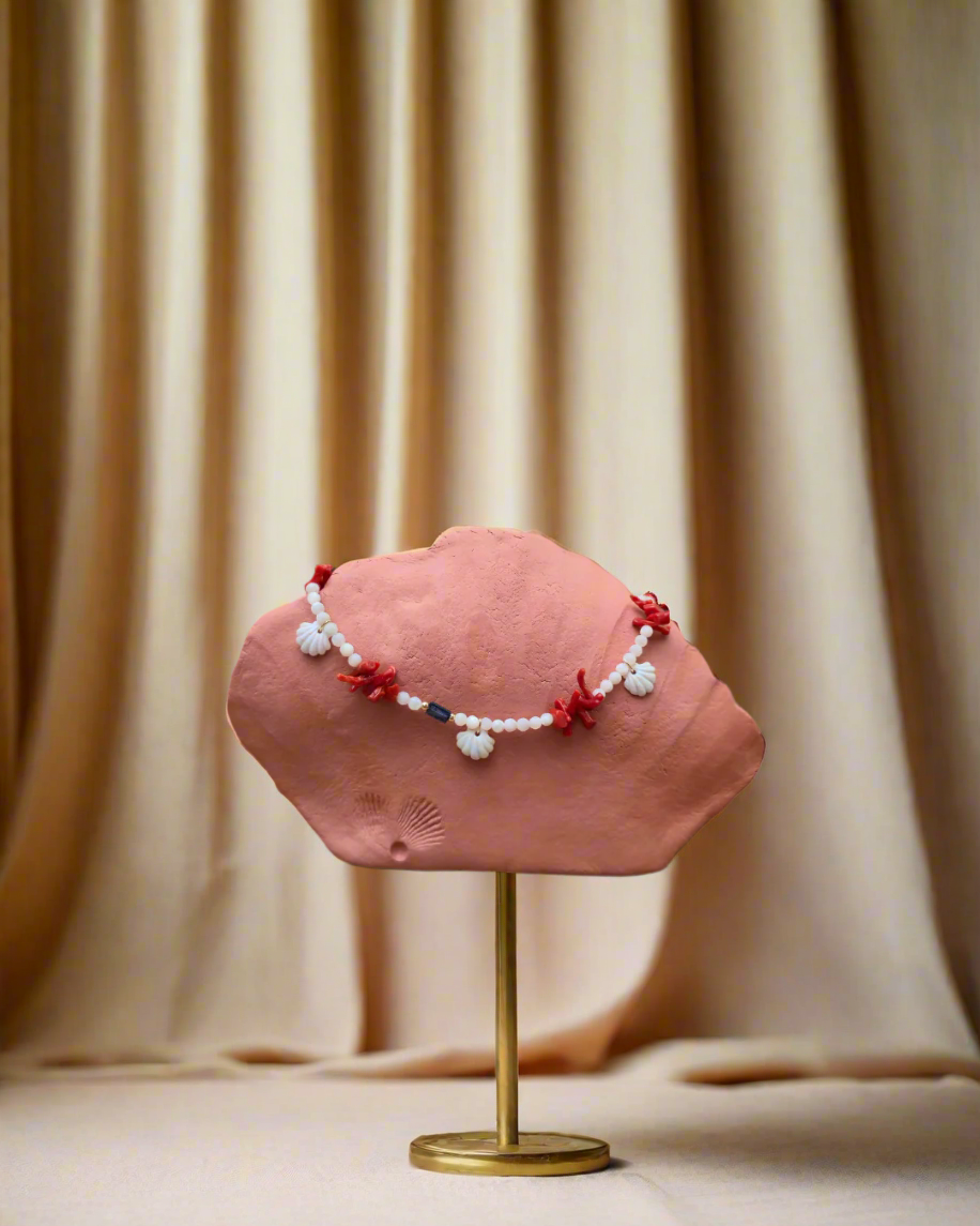 Pink hat with decorative elements on a stand against a beige curtain background