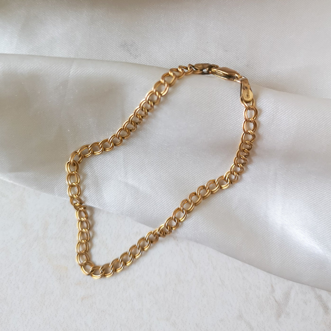 Gold chain bracelet on a white fabric background
